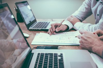 Two people reviewing documents together at laptops