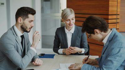 Business partners reviewing and signing an agreement at a table